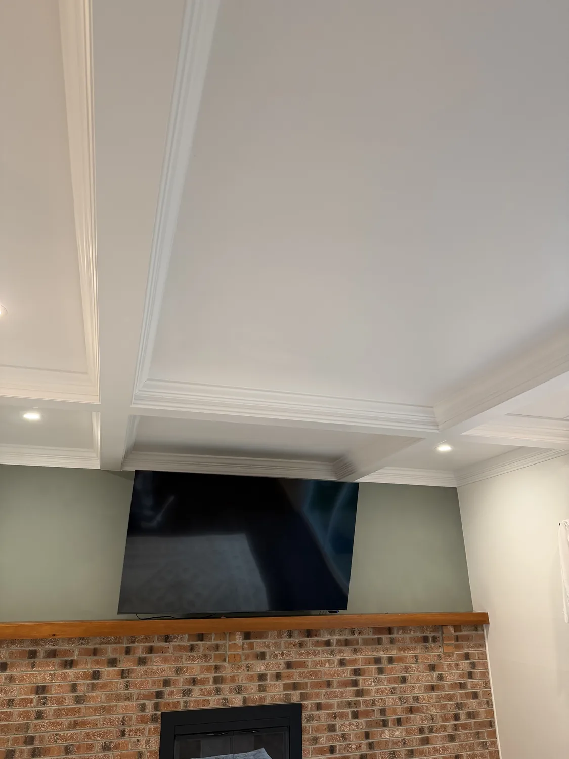 Finished coffered ceiling over a fireplace and mounted TV by LM Legacy Remodeling