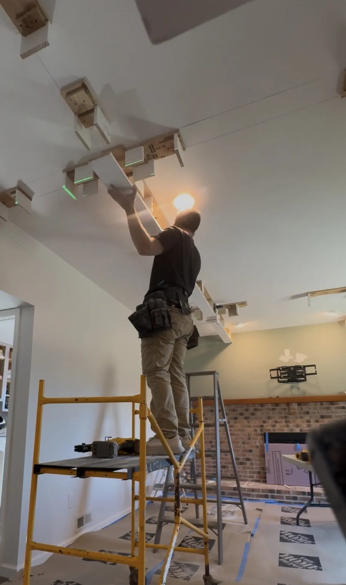 Installing the first beam of a coffered ceiling against laser-leveled ceiling framing