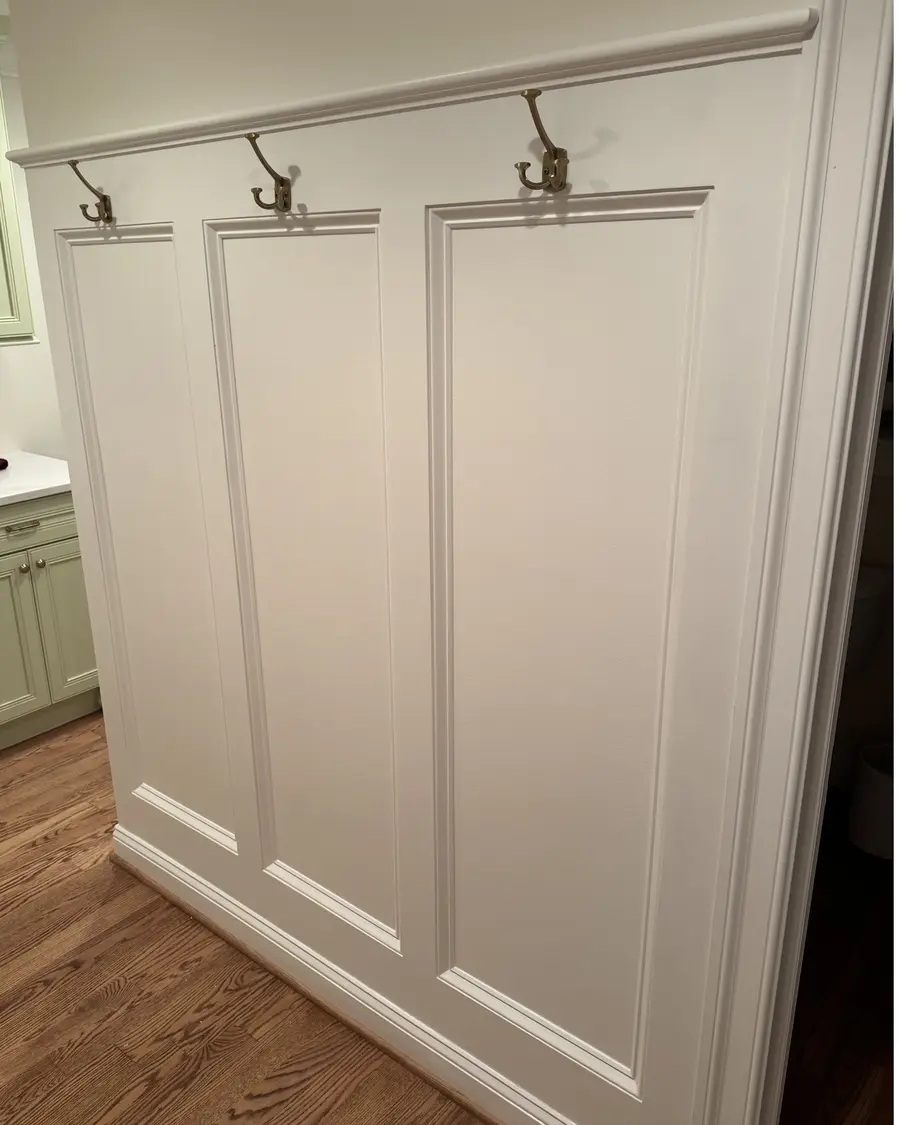 Paneled wainscoting with cap rail and brass coat hooks